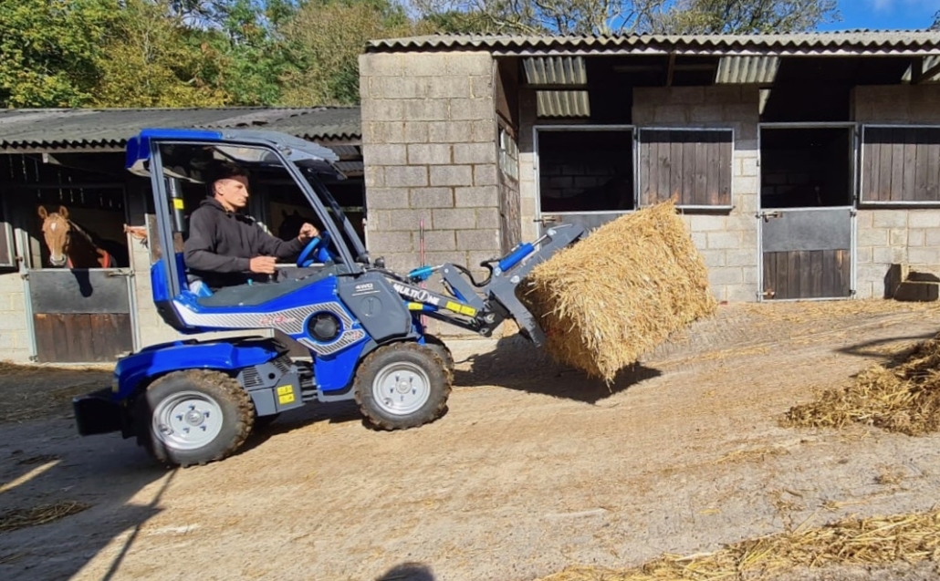 MultiOne mini loader 2 series with grapple moving a hay bale