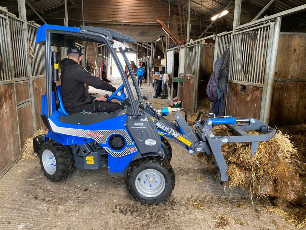 MultiOne mini loader 2 series with grapple putting hay in a stable